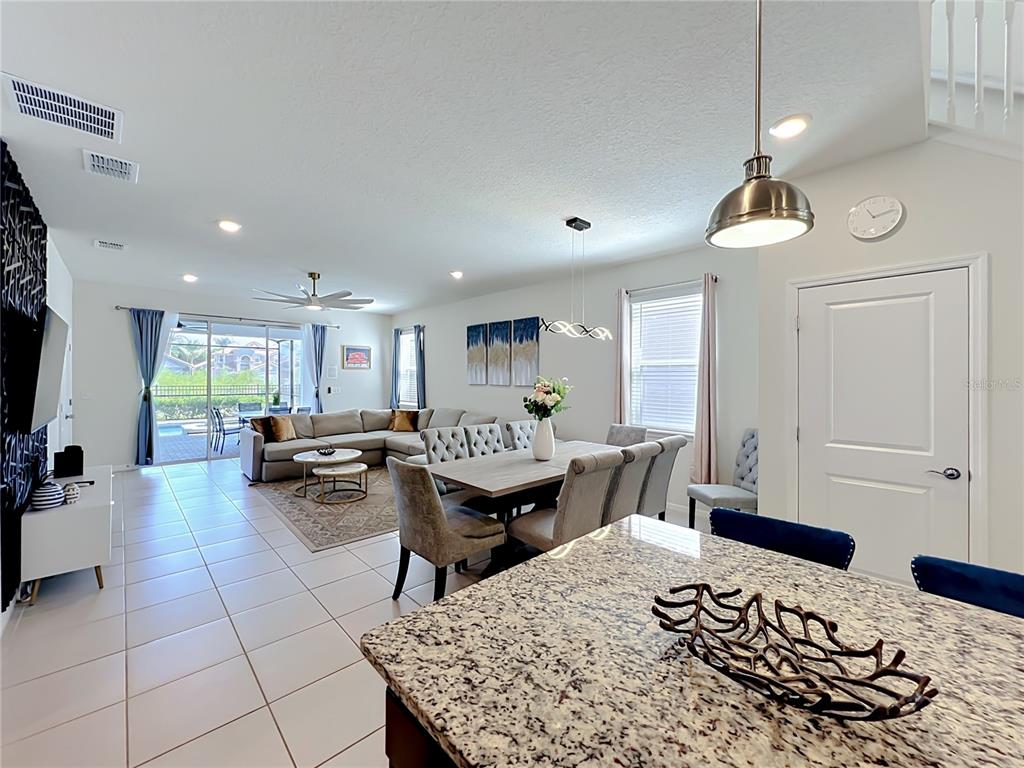 An open-concept living and dining area features tile floors, granite countertops, and a sliding glass door — 4033 LANA AVENUE, DAVENPORT, FL