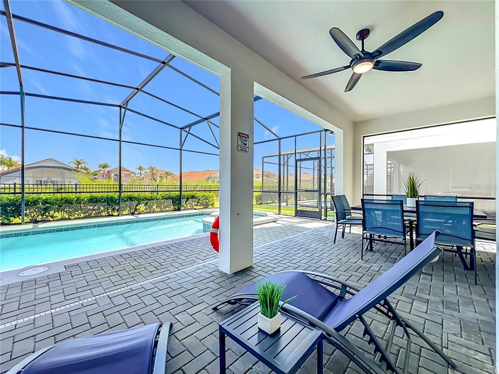 A covered patio features a swimming pool, lounge chairs, dining furniture, and a ceiling fan — 4033 LANA AVENUE, DAVENPORT, FL