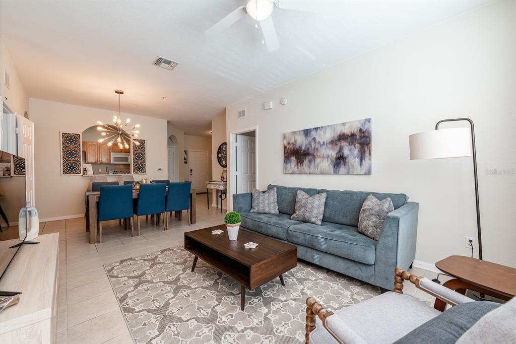 A living room with a blue sofa, coffee table, and adjacent dining area — 2778 ALMATON LOOP UNIT 204, KISSIMMEE, FL