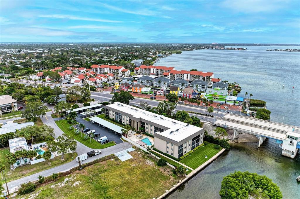 An aerial view shows a multi-story apartment building, parking lot, and bridge near water — 6470 HOLLYWOOD BOULEVARD UNIT 307, SARASOTA, FL
