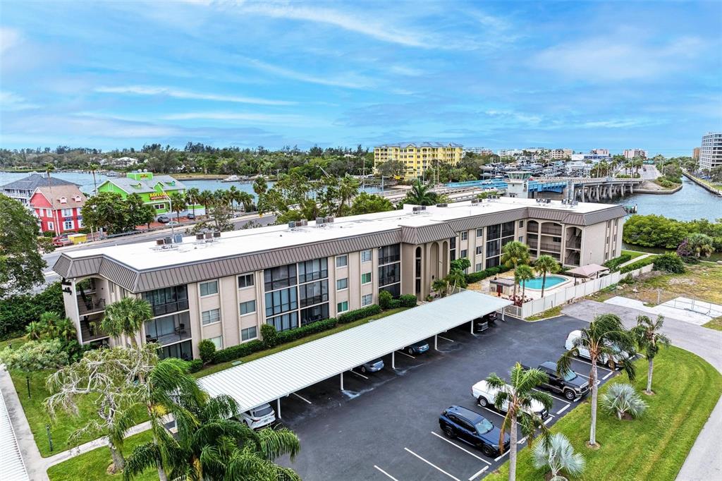 An aerial view shows a multi-story apartment building with a parking lot and swimming pool — 6470 HOLLYWOOD BOULEVARD UNIT 307, SARASOTA, FL