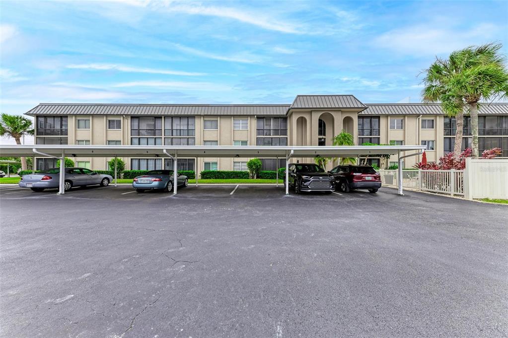 A multi-story apartment building features a covered parking area with several parked cars — 6470 HOLLYWOOD BOULEVARD UNIT 307, SARASOTA, FL