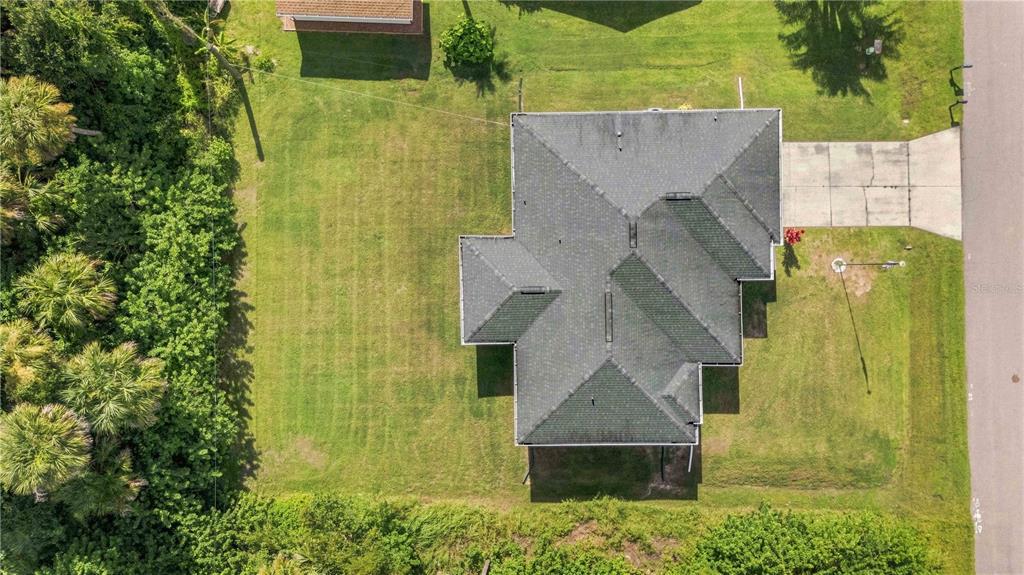 An aerial view shows a house with a dark shingled roof on a grassy lot — 22437 ADORN AVENUE, PORT CHARLOTTE, FL