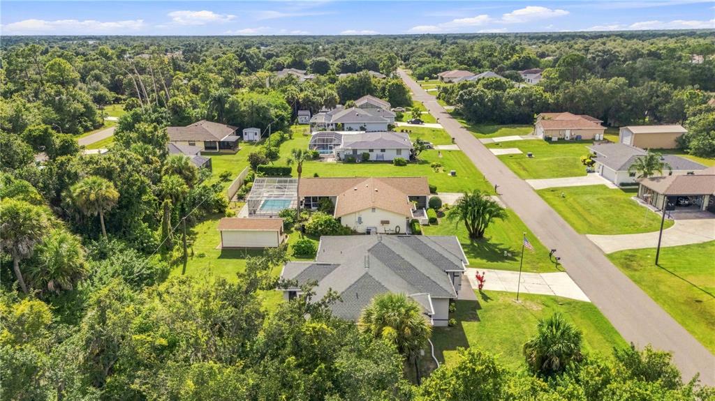 An aerial view shows a suburban neighborhood with single-family homes, swimming pools, and lush trees — 22437 ADORN AVENUE, PORT CHARLOTTE, FL