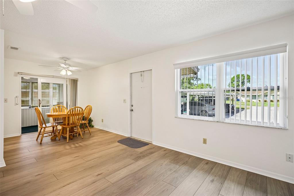 A dining area with wood-look flooring, a ceiling fan, a sliding glass door, and windows — 2224 GRENADIER DRIVE, SUN CITY CENTER, FL
