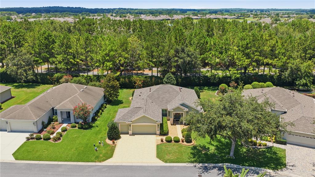 An aerial view shows three suburban houses with paved driveways and green lawns near trees — 9383 SW 71ST LOOP, OCALA, FL