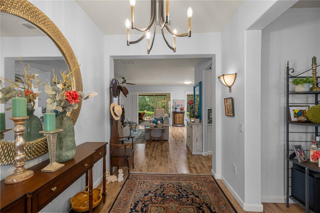 A foyer with a chandelier, a large round mirror, and a view into the living area — 9383 SW 71ST LOOP, OCALA, FL