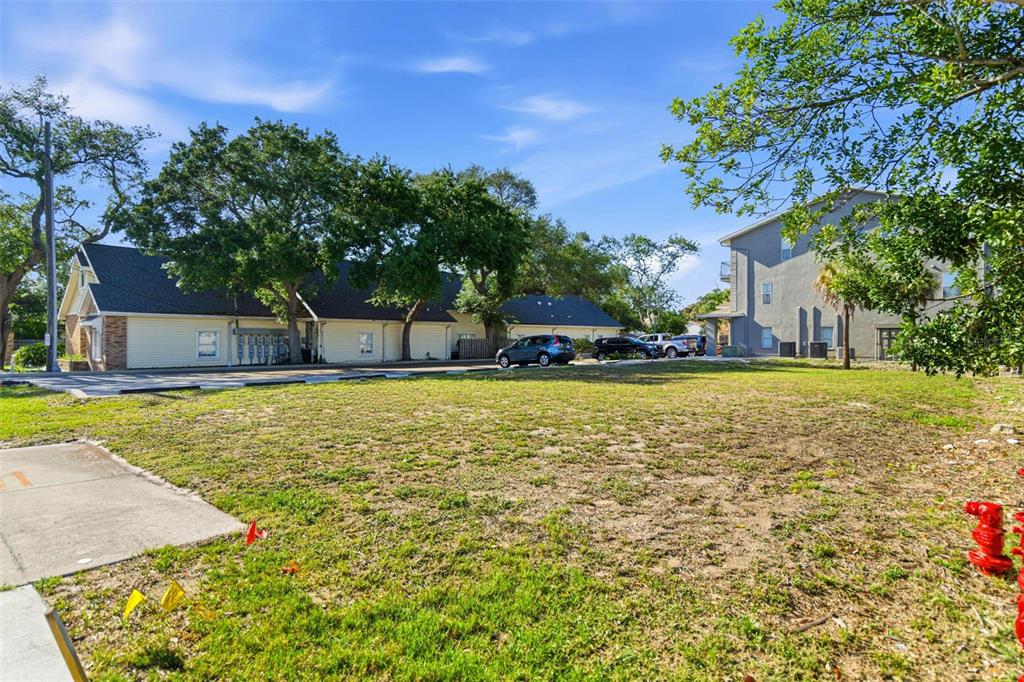 A vacant grassy lot sits in front of a residential building and parking area — 444 SKINNER BOULEVARD, DUNEDIN, FL