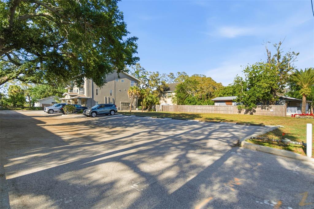 An outdoor parking lot with several parked cars sits next to a residential building — 444 SKINNER BOULEVARD, DUNEDIN, FL