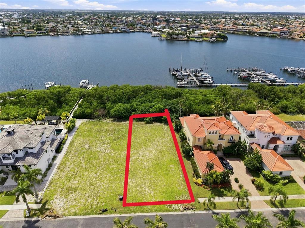 An aerial view shows a vacant rectangular waterfront lot outlined in red between two houses — 6111 LAGOMAR LANE, APOLLO BEACH, FL