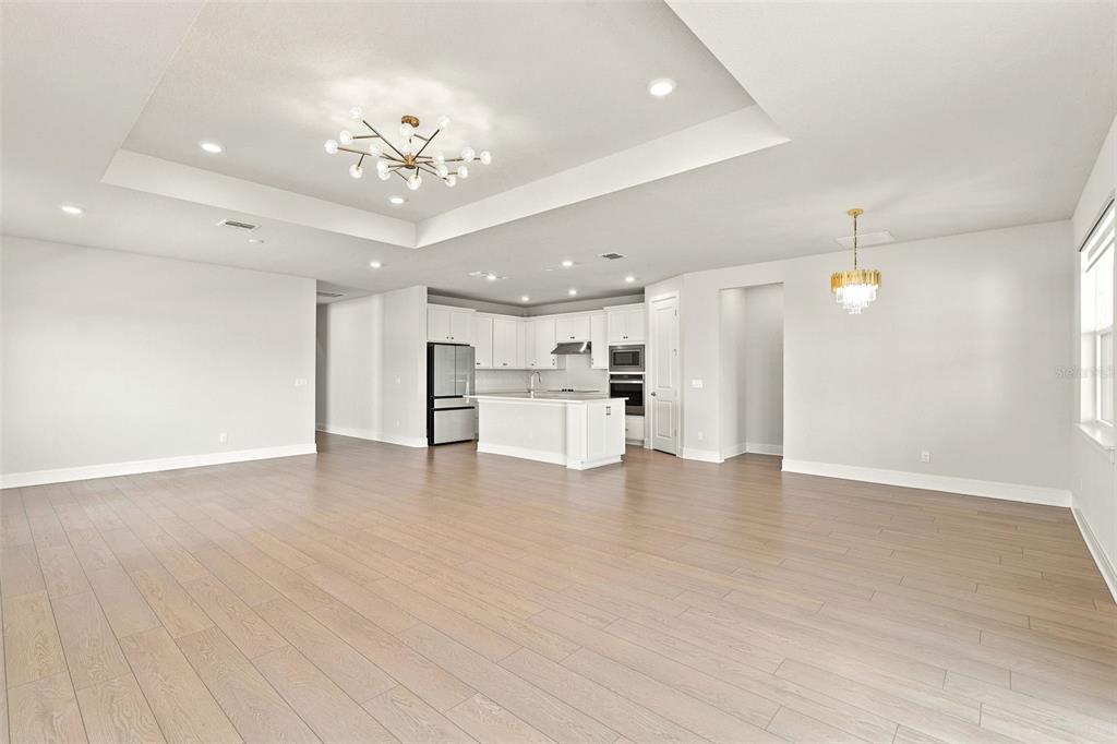 A spacious open-concept kitchen and living area with light wood floors and white cabinetry — 1803 GROVELINE ROAD, ST CLOUD, FL
