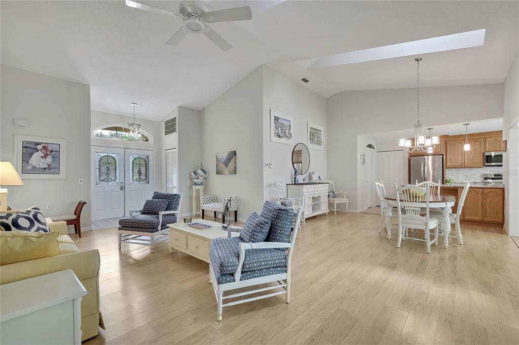 A bright, open-concept living and dining area features light wood flooring and a vaulted ceiling — 2356 ROLLING VIEW DRIVE, SPRING HILL, FL