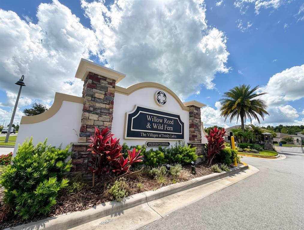 A single-story house with a brown garage, stone accents, and a paved driveway at sunset — 11767 LAKE BOULEVARD, NEW PORT RICHEY, FL