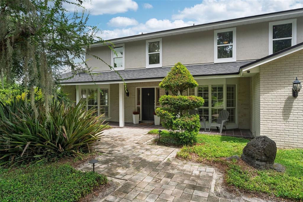 A two-story house with a brick facade, a paved walkway, and a manicured topiary tree — 2260 W CLASSIC COURT, LONGWOOD, FL