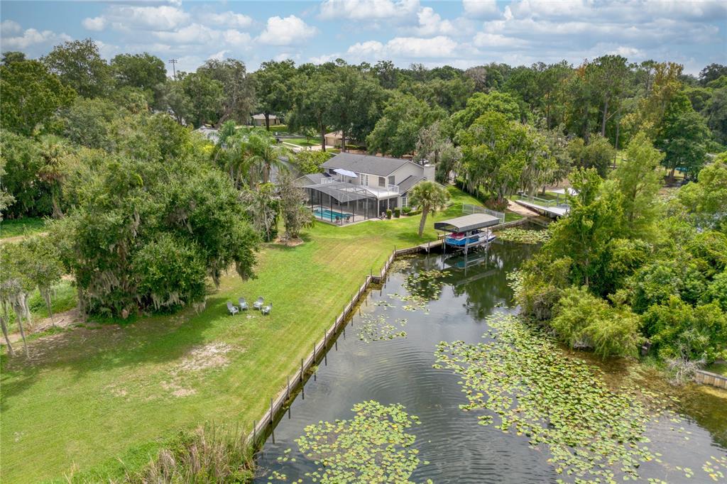 An aerial view shows a two-story house with a pool, dock, and canal — 2260 W CLASSIC COURT, LONGWOOD, FL