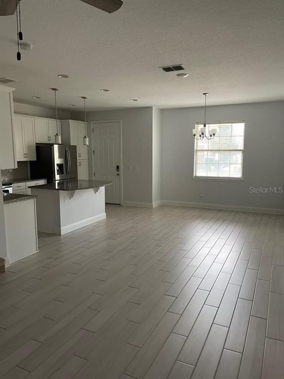 A kitchen with white cabinets and a breakfast bar opens to a dining area — 14284 SWANLEY STREET, ORLANDO, FL
