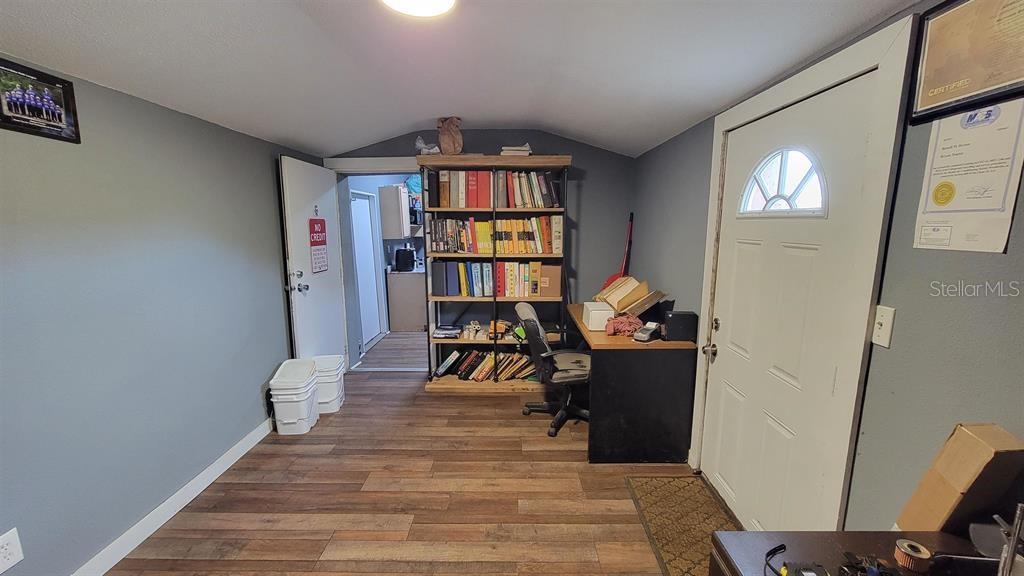 A room with wood-look flooring, a bookshelf, a desk, and a door leading to another area — 26208 COUNTY ROAD 49, O'BRIEN, FL