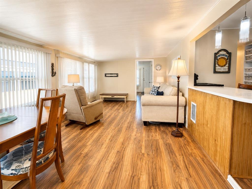 A living and dining area features wood-look flooring, a beige sofa, and a recliner — 6921 MARLIN LANE, BRADENTON, FL