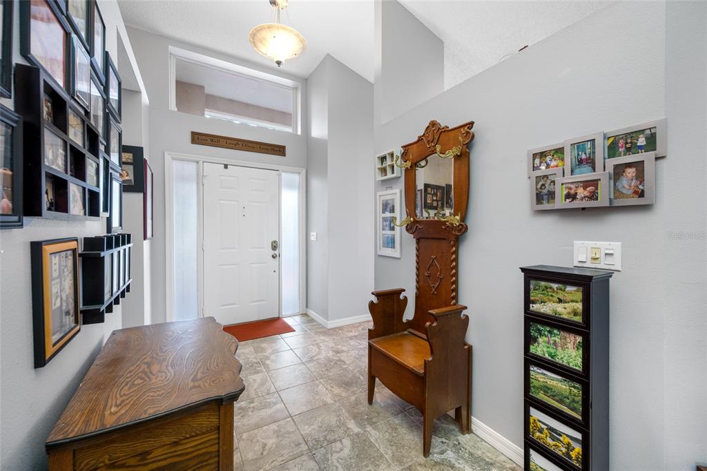 A tiled entryway features a wooden hall tree, a console table, and walls decorated with photos — 1044 DALESIDE LANE, NEW PORT RICHEY, FL