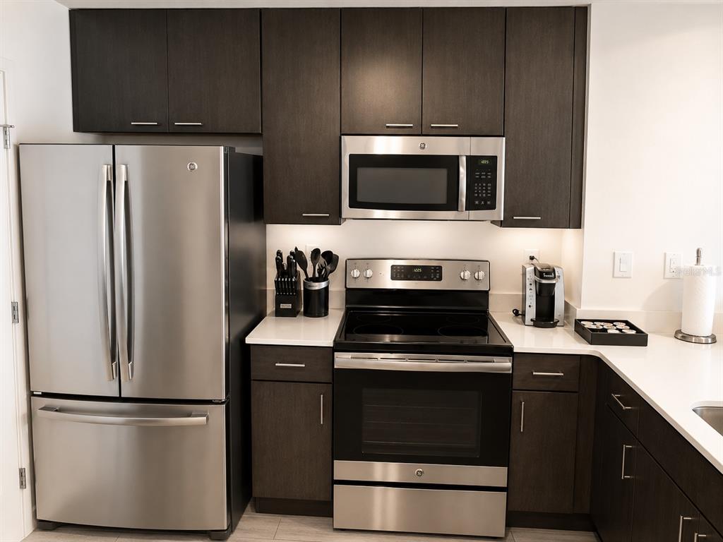 A kitchen features dark wood cabinets, stainless steel appliances, and white countertops — 14501 GROVE RESORT AVE, WINTER GARDEN, FL
