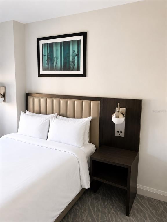 A hotel bedroom features a bed with a tufted headboard, a nightstand, and wall art — 14501 GROVE RESORT AVE, WINTER GARDEN, FL