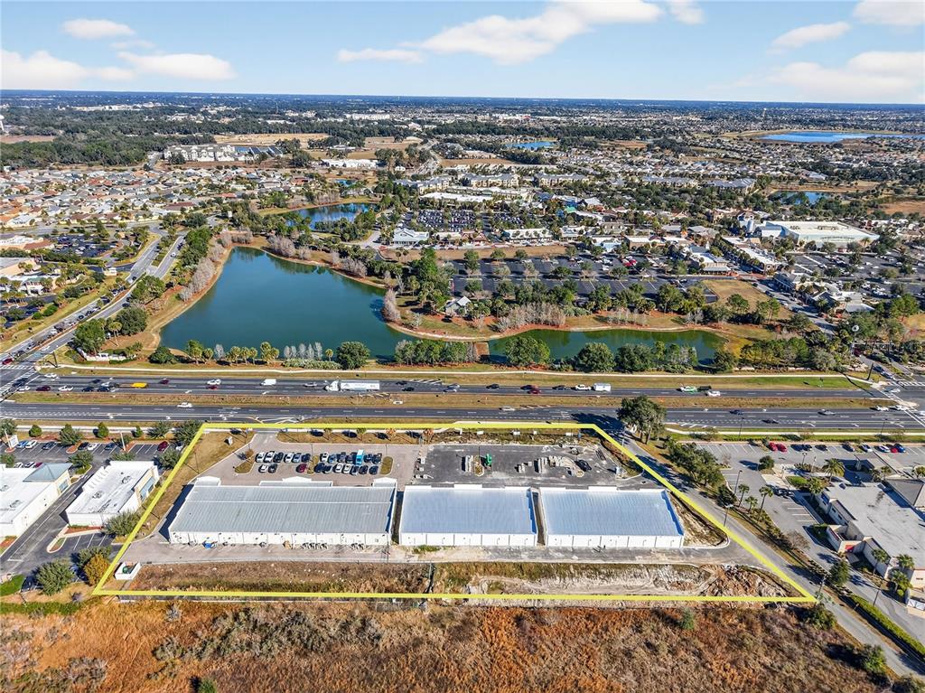 An aerial view shows a commercial building with a large parking lot near a highway — 4713 E STATE ROAD 44, WILDWOOD, FL