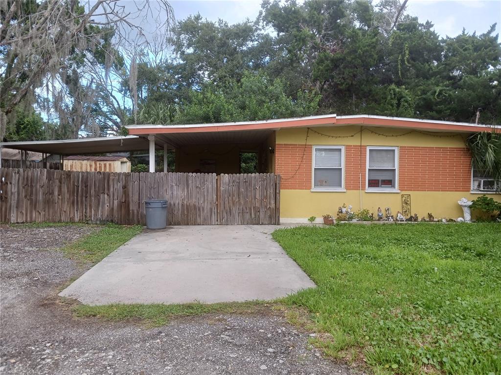 A single-story house with a yellow and orange facade, a carport, and a wooden fence — 5115 GREEN KEY ROAD, NEW PORT RICHEY, FL