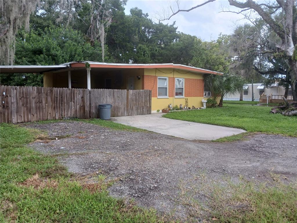 A single-story house with a yellow and brick exterior features a carport and wooden fence — 5115 GREEN KEY ROAD, NEW PORT RICHEY, FL