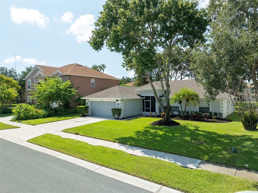A single-story house with a two-car garage and a large tree in the front yard — 1373 PAYETTE LANE, WEST MELBOURNE, FL