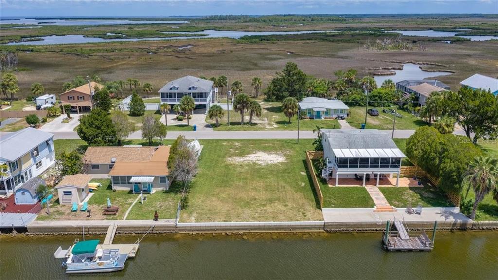 An aerial view shows a vacant waterfront lot situated between two houses with private docks — 4018 EAGLE NEST DRIVE, HERNANDO BEACH, FL
