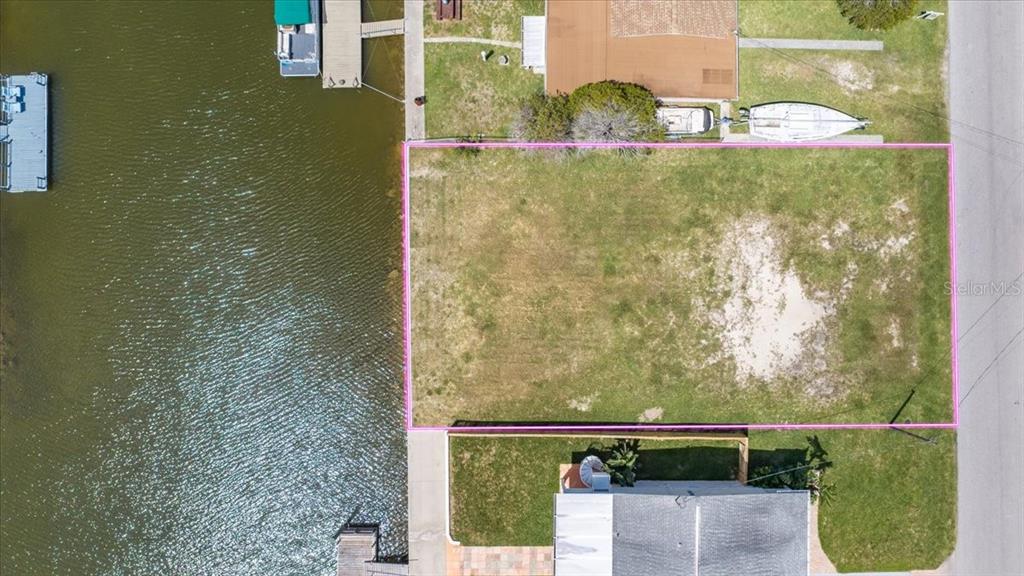 An aerial view shows a vacant waterfront lot outlined in pink next to a canal — 4018 EAGLE NEST DRIVE, HERNANDO BEACH, FL