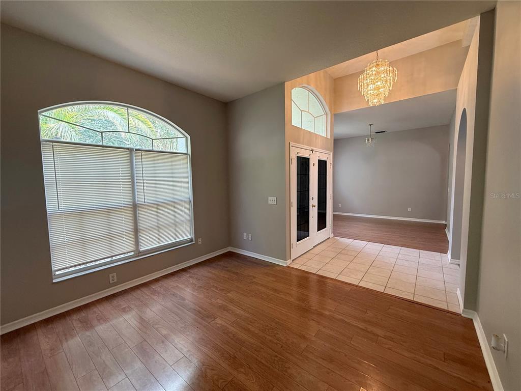 A room with wood flooring, a large arched window, and a tiled entryway with double doors — 3510 AUTUMN GLEN DRIVE, VALRICO, FL