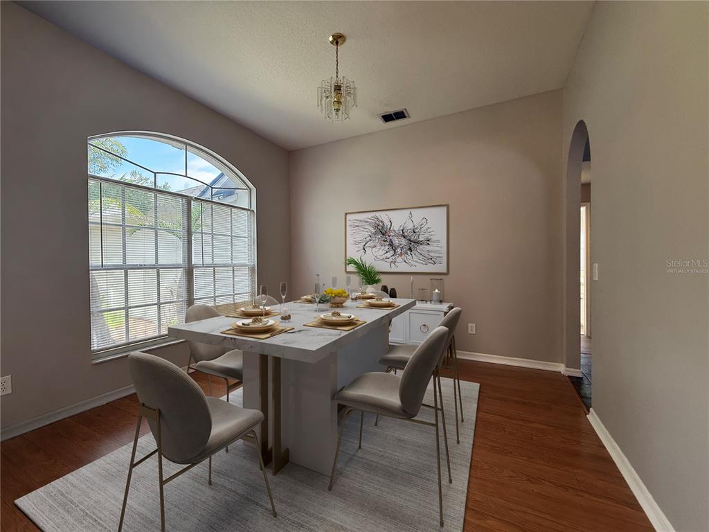 A dining room features a marble-topped table, arched window, and hardwood flooring — 3510 AUTUMN GLEN DRIVE, VALRICO, FL