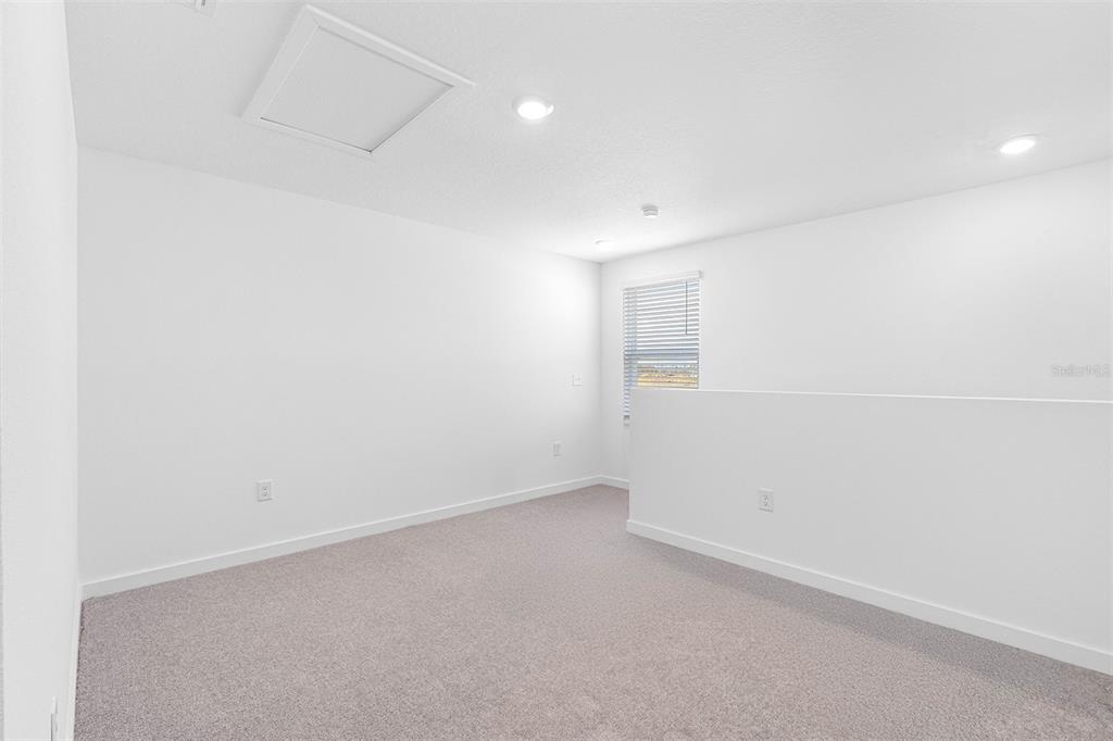 A carpeted loft area features white walls, recessed lighting, and a window with blinds — 5277 CAP ROAD, BROOKSVILLE, FL