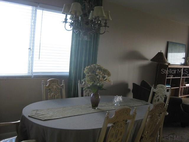 A dining room features a round table with chairs, a chandelier, and a window with blinds — 3510 S OCEAN SHORE BOULEVARD UNIT 304, FLAGLER BEACH, FL