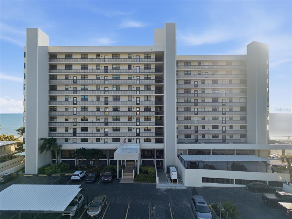 An exterior view of a multi-story apartment building with a parking lot in front — 15462 GULF BOULEVARD UNIT 406, ST PETERSBURG, FL