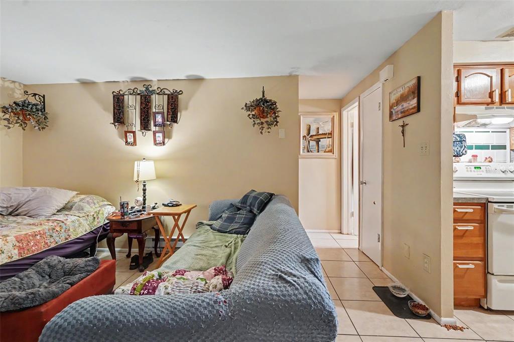 A living area with a bed, a blue sofa, and a view into the kitchen — 5513 OCEANIC ROAD, HOLIDAY, FL