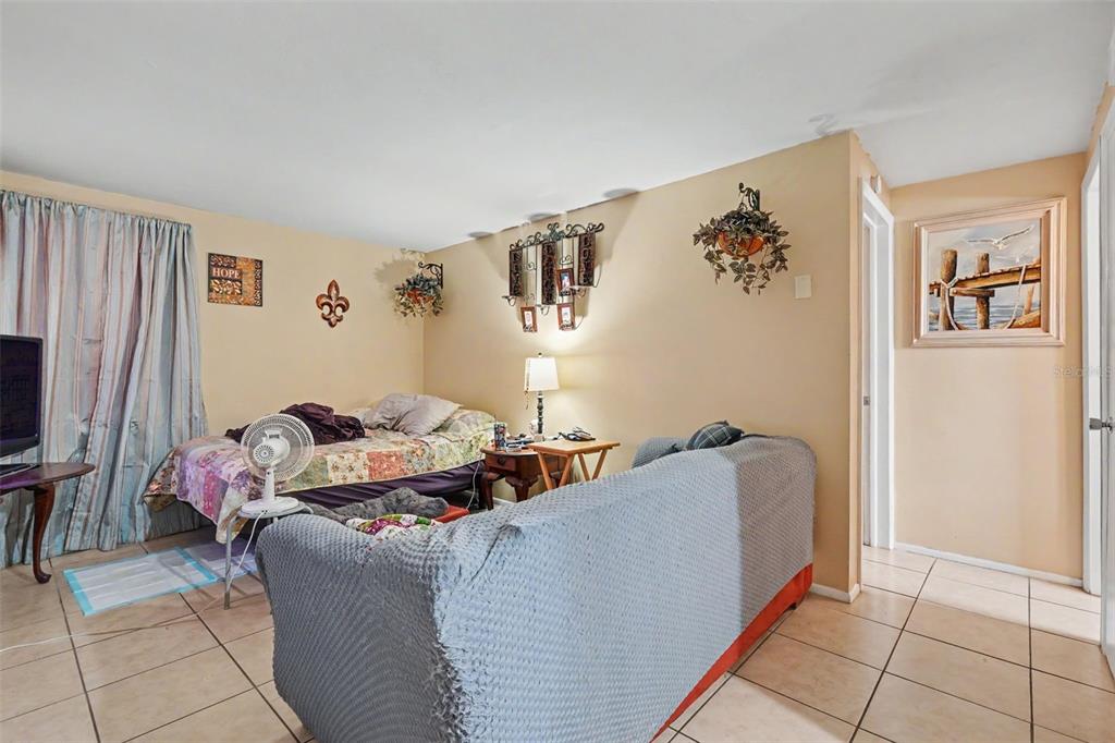 A room with tile flooring, a bed, a sofa, and wall decor in a neutral space — 5513 OCEANIC ROAD, HOLIDAY, FL