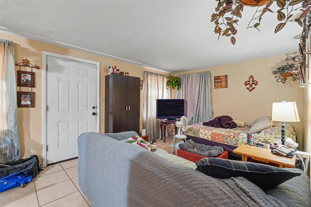 A living room with tile floors, a sofa, a bed, and a television on a stand — 5513 OCEANIC ROAD, HOLIDAY, FL