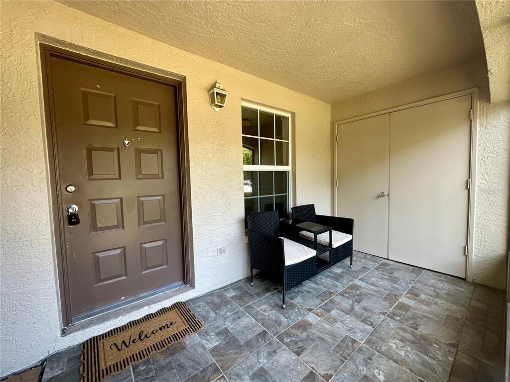 A screened-in patio features tiled flooring, two black chairs, and a storage closet — 3004 BONAVENTURE CIRCLE UNIT 102, PALM HARBOR, FL