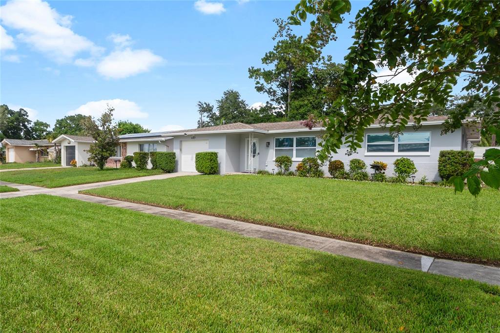 A single-story gray house with a white garage and a manicured front lawn — 487 LAKE HILL LANE, LARGO, FL
