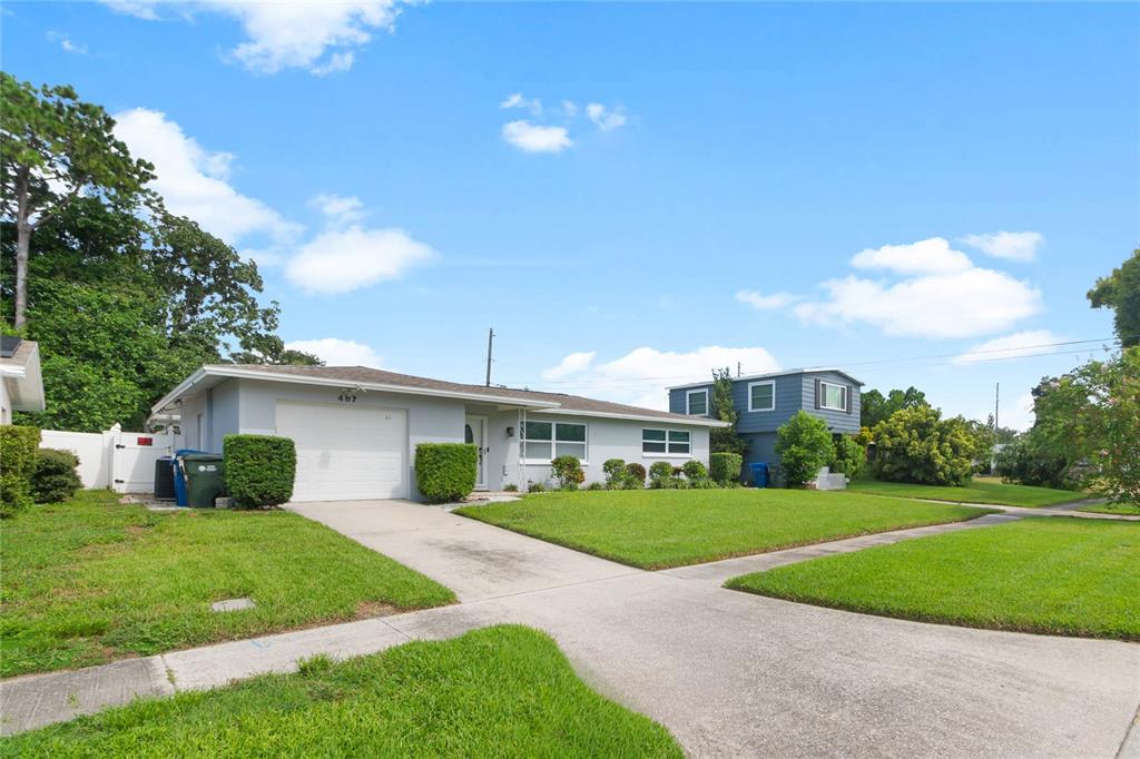 A single-story house with a white garage, gray exterior, and a green lawn — 487 LAKE HILL LANE, LARGO, FL