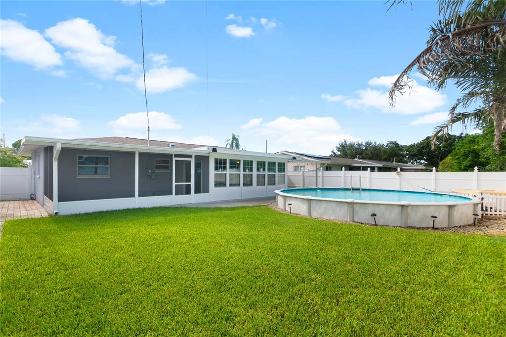 A backyard features a lawn, a white fence, and an above-ground swimming pool — 487 LAKE HILL LANE, LARGO, FL