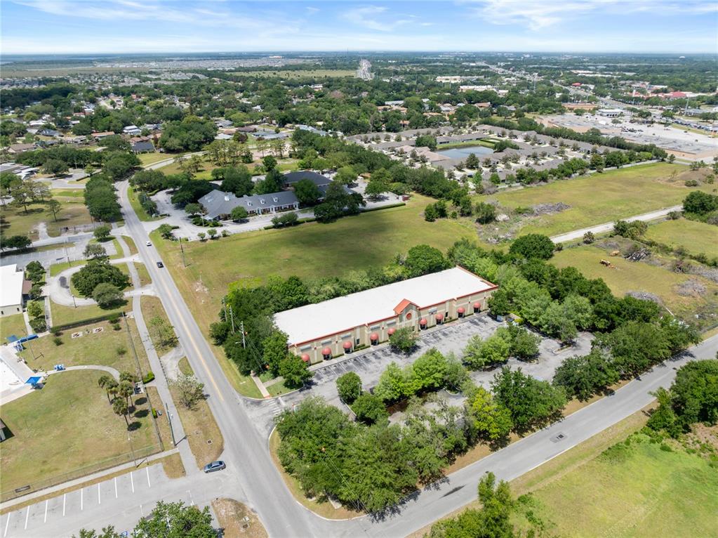 An aerial view shows a commercial building with a parking lot surrounded by green space — 3002 17TH STREET, ST CLOUD, FL