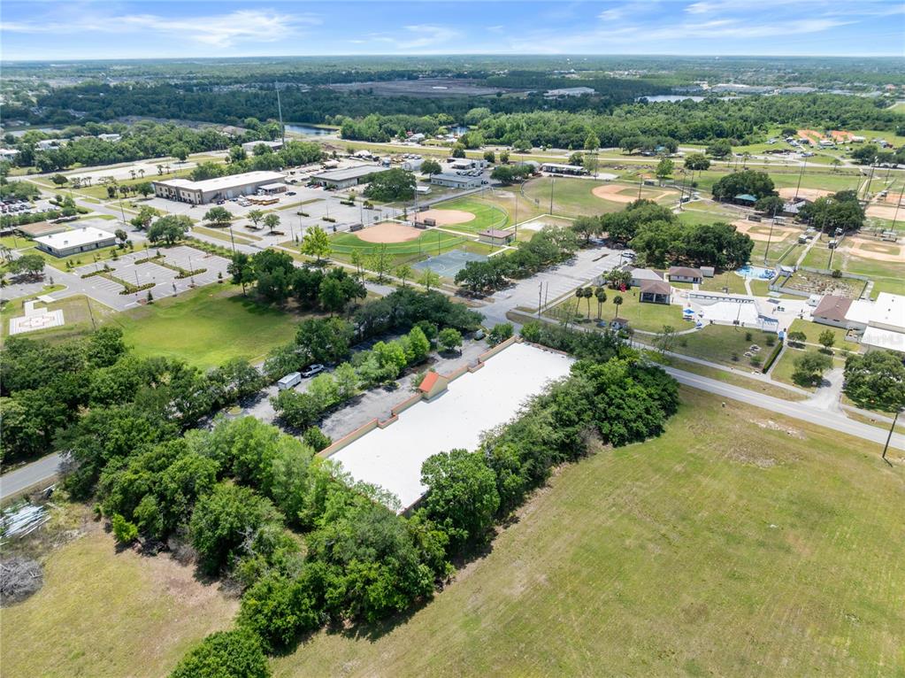 An aerial view shows a commercial building with a white roof surrounded by trees — 3002 17TH STREET, ST CLOUD, FL