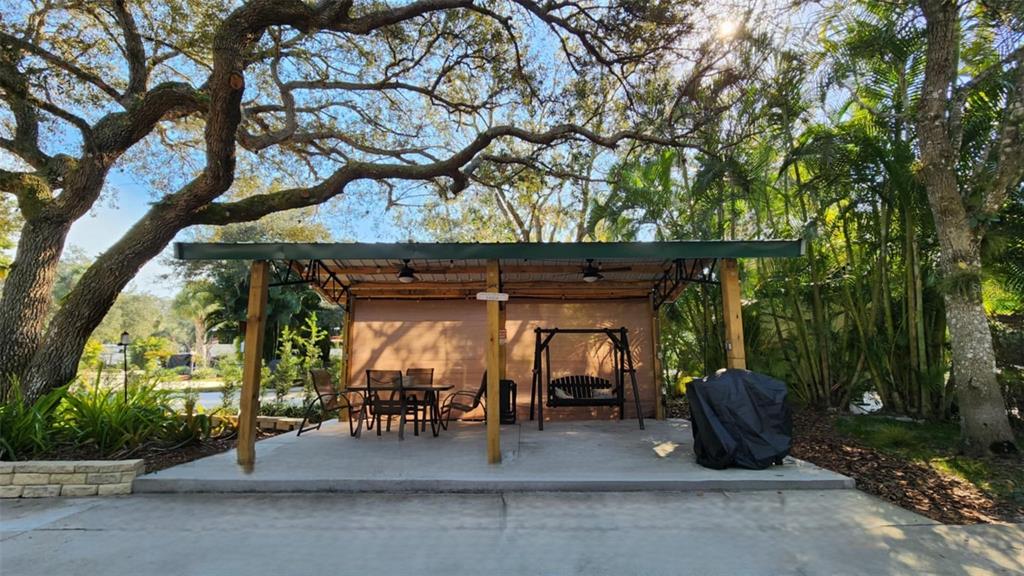A covered outdoor patio features a dining set, a porch swing, and a grill cover — 253 SADDLE LANE, RIVER RANCH, FL