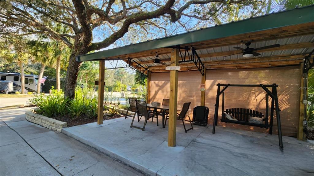 A covered outdoor patio features a dining set, a porch swing, and ceiling fans — 253 SADDLE LANE, RIVER RANCH, FL