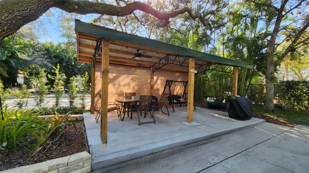 A covered outdoor patio features a dining set, a swing, and a grill on concrete — 253 SADDLE LANE, RIVER RANCH, FL