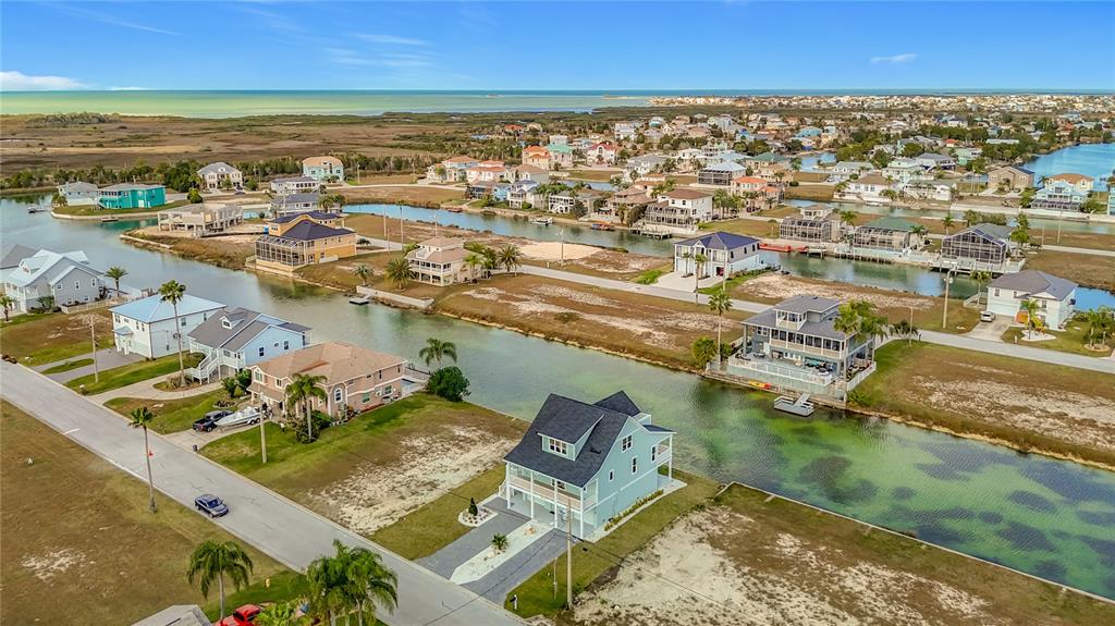 An aerial view shows waterfront houses along a canal leading toward the open bay — 3487 SHEEPHEAD DRIVE, HERNANDO BEACH, FL