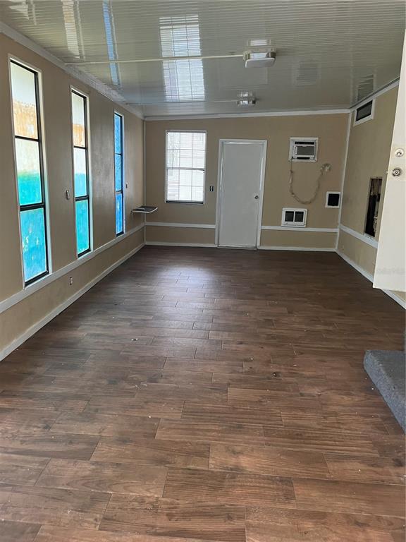 A sunroom with wood-look tile flooring, beige walls, and multiple windows — 3000 CLARCONA ROAD UNIT 2824, APOPKA, FL